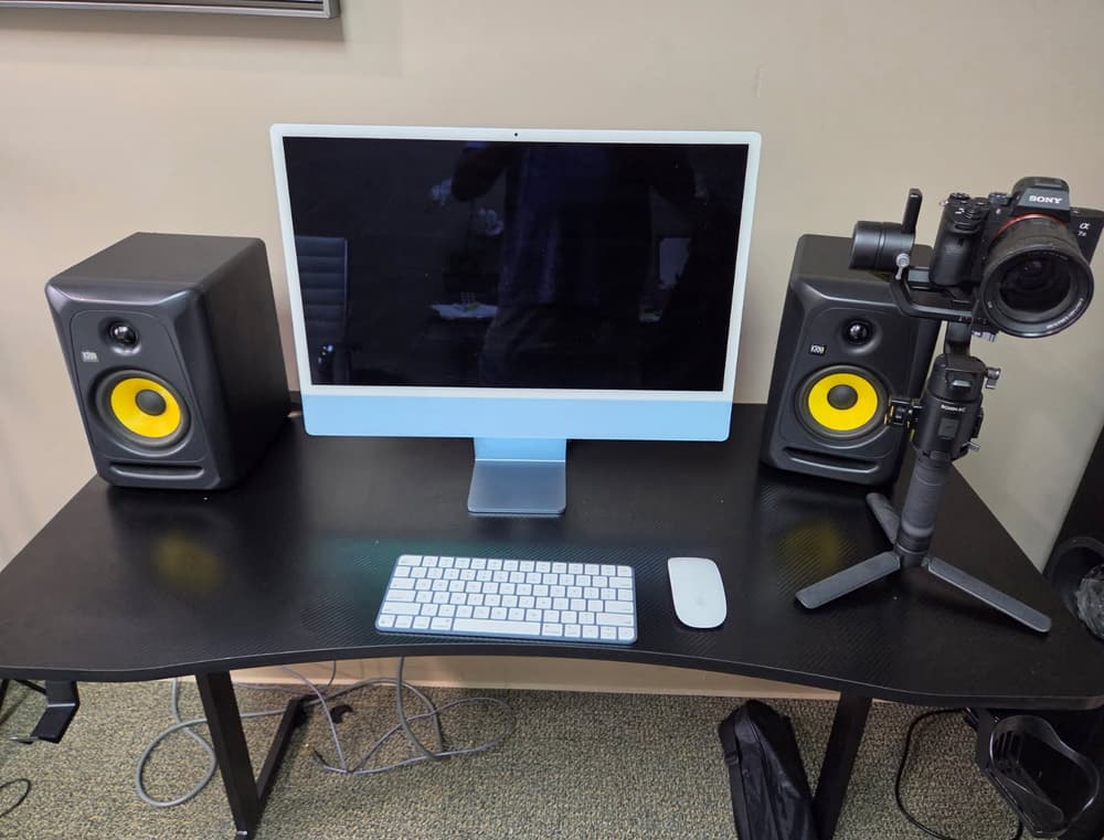 The N My Lane Ent edit bay — iMac flanked by KRK studio monitors, with the camera and gimbal rig on the desk